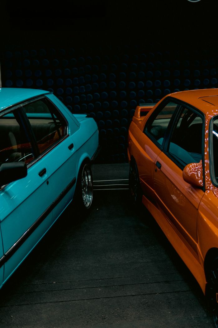 Services-02 Close-up of vintage BMW E28 and E30 models displayed at an indoor car exhibition.
