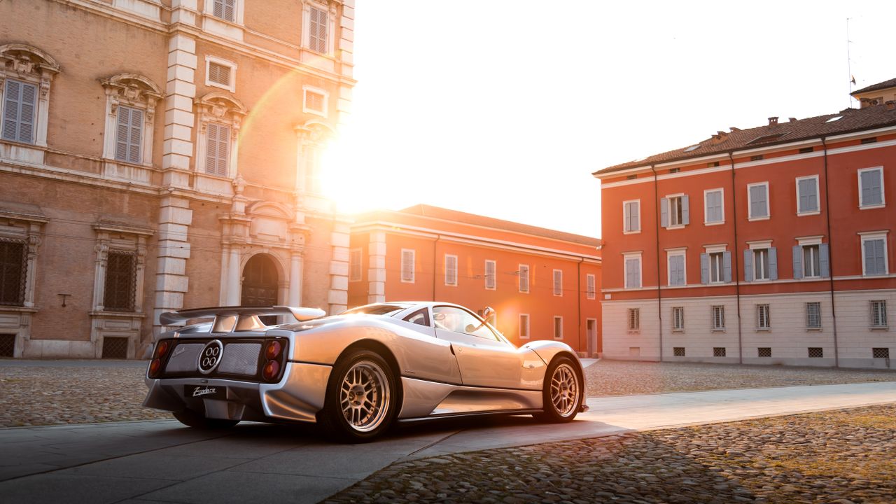 why-choose-us Elegant silver car parked in a historic European courtyard, beautifully illuminated by the sunset.